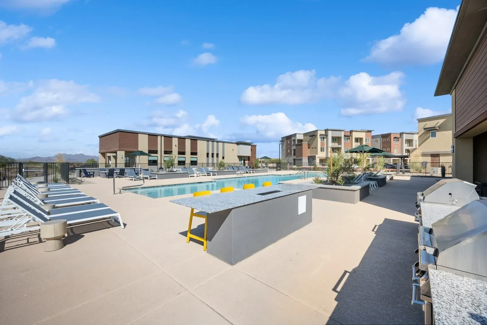 Resort-style swimming pool with lounge chairs, outdoor bar, and grills at Longbow Luxury Apartments Mesa, AZ.