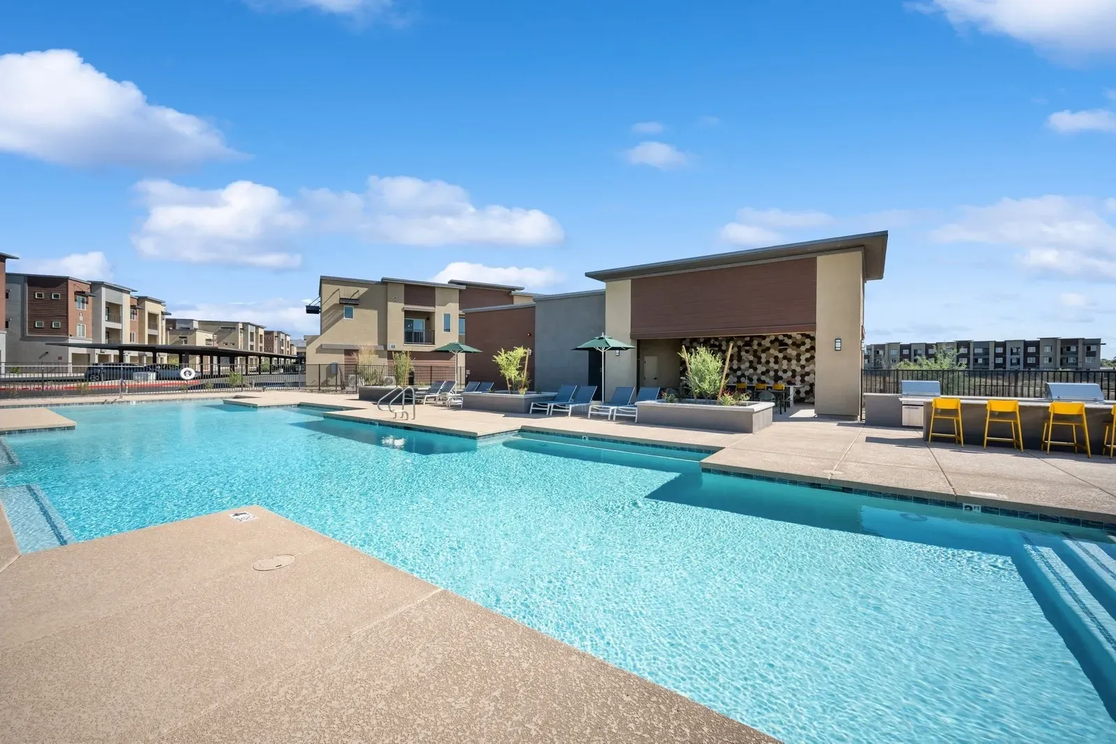 Resort-style swimming pool with lounge chairs and an outdoor kitchen at Longbow Luxury Apartments Mesa, AZ.