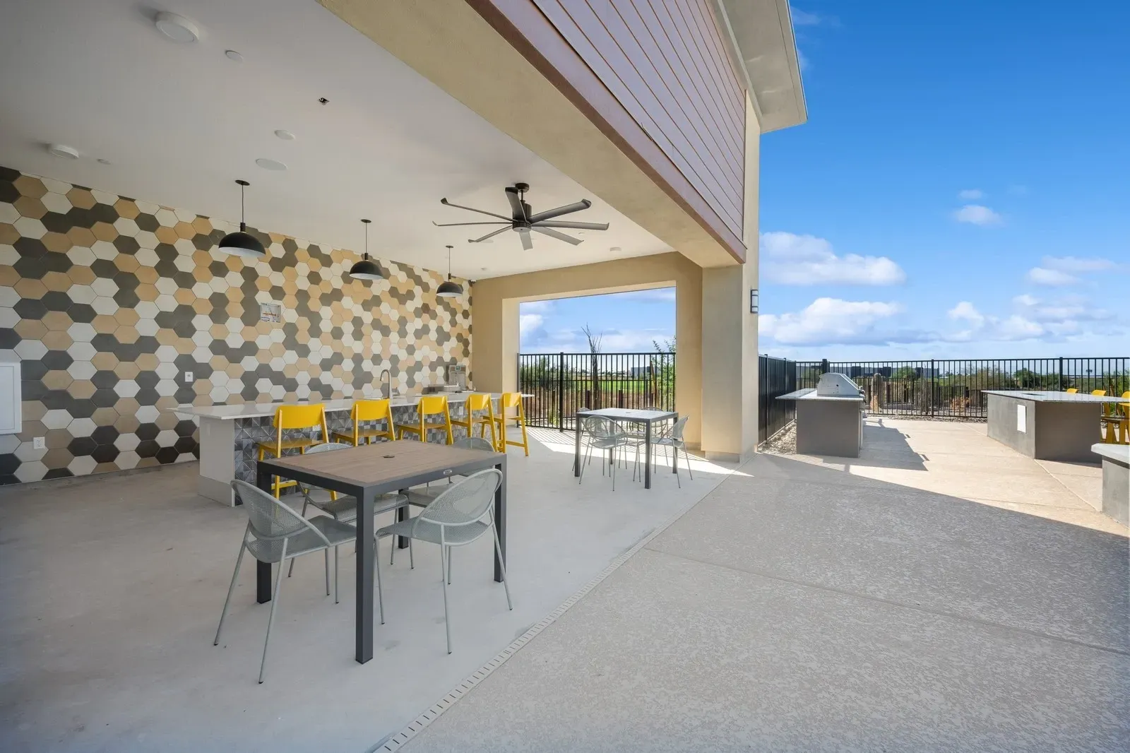 Outdoor kitchen and dining area with bar seating, grills, and tables.