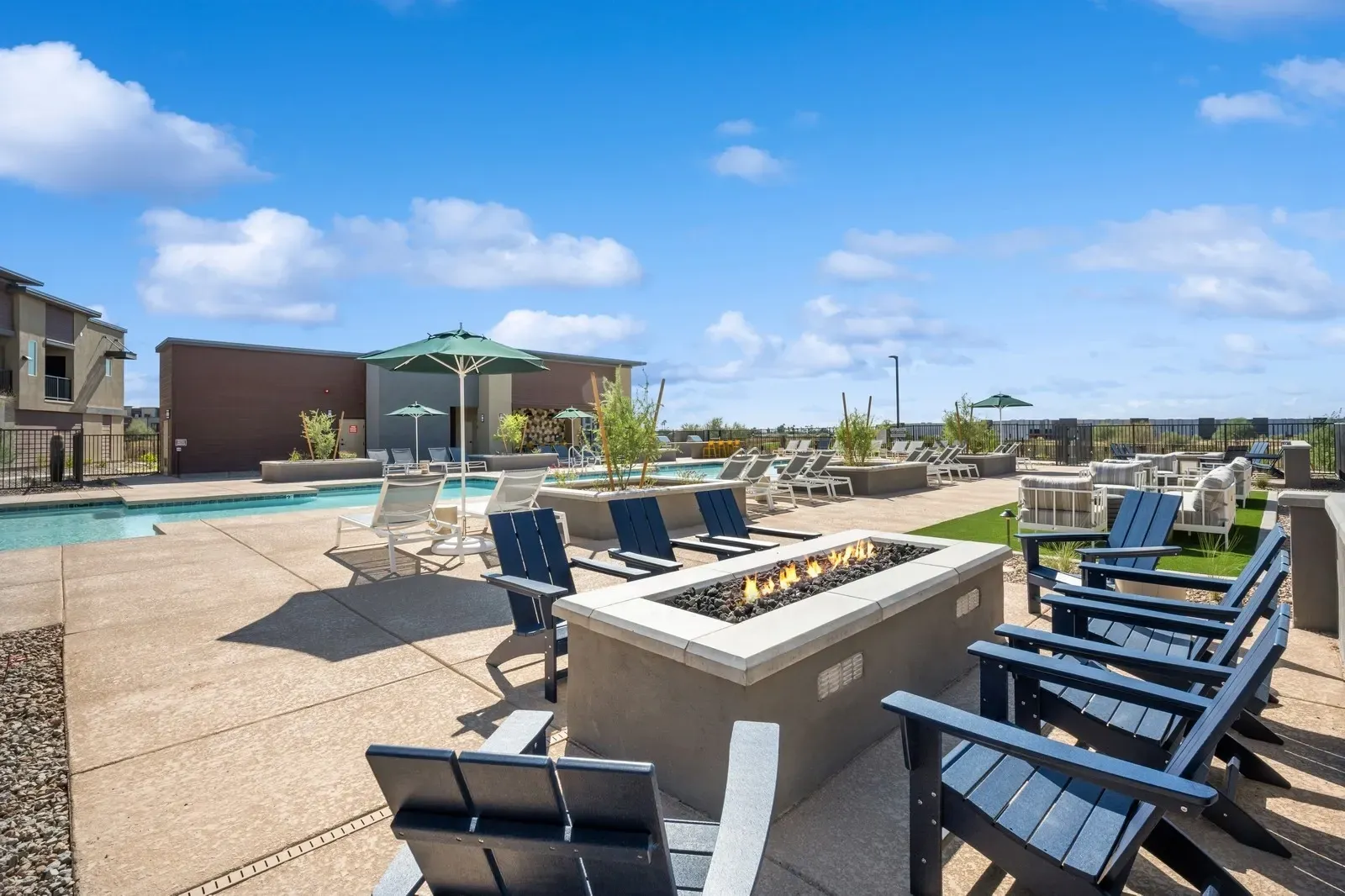 Outdoor patio with a fire pit and lounge chairs next to a swimming pool.
