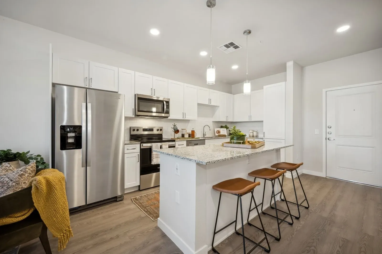 Modern kitchen with stainless steel appliances, granite countertops, and island with bar stools  at Longbow Luxury Apartments Mesa, AZ.