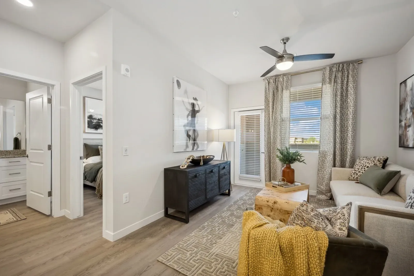Open-concept living area with a couch, armchair, coffee table, and a view into the kitchen and bedroom at Longbow Luxury Apartments Mesa, AZ.