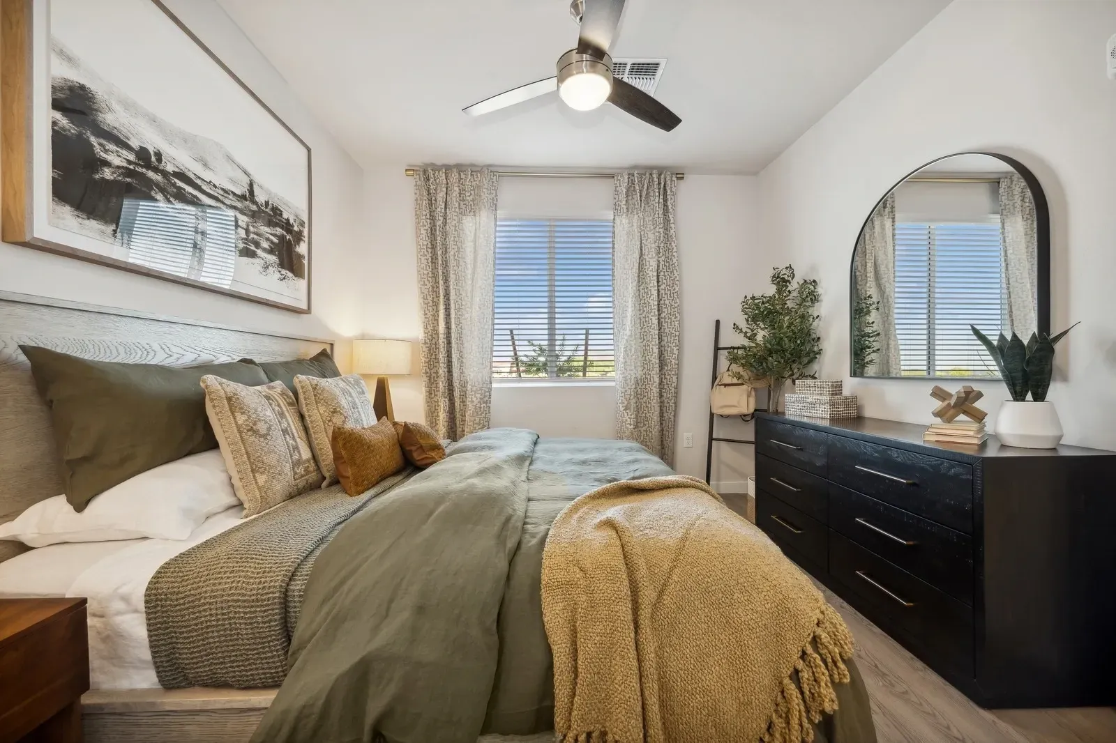 Stylish bedroom with a king-size bed, dresser, and large framed artwork at Longbow Luxury Apartments Mesa, AZ.