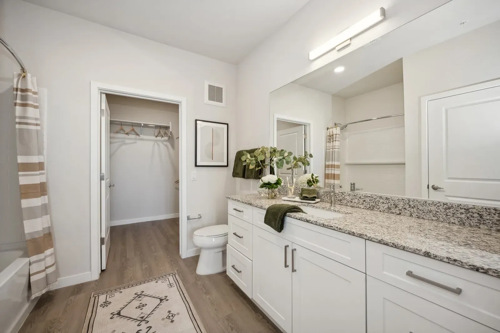 Modern bathroom with white vanity, granite countertops, toilet, and walk-in closet at Longbow Luxury Apartments Mesa, AZ.
