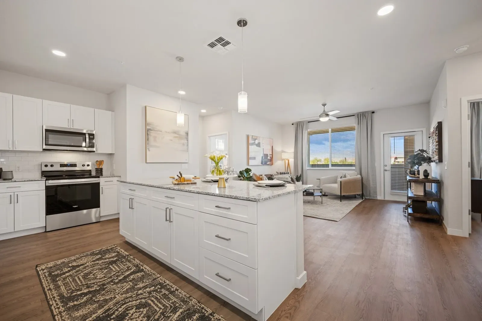Modern kitchen with granite island and stainless steel appliances, open to living area at Longbow Luxury Apartments Mesa, AZ.