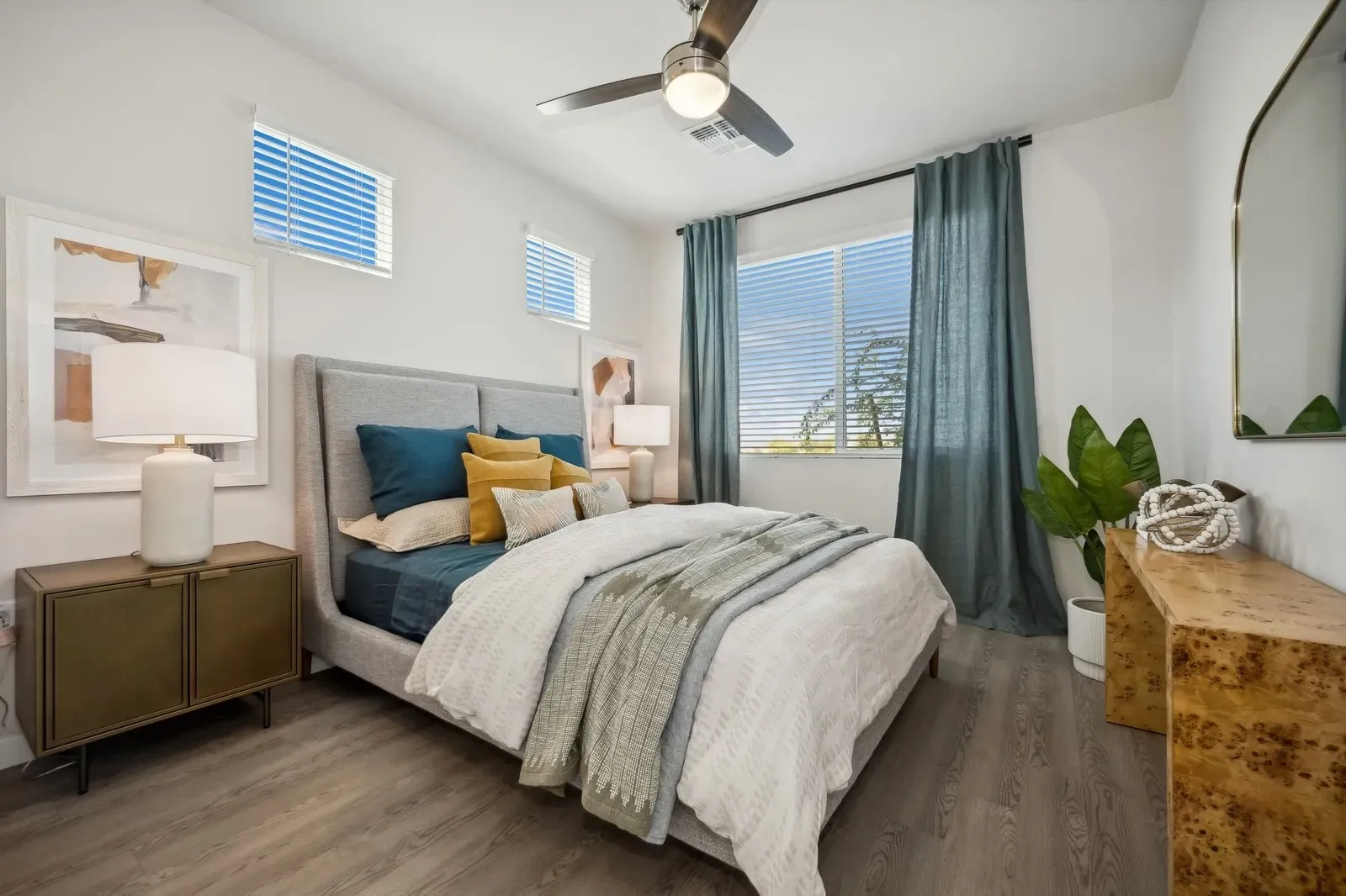 Bedroom with a king-size bed, nightstand, dresser, and a ceiling fan at Longbow Luxury Apartments Mesa, AZ.