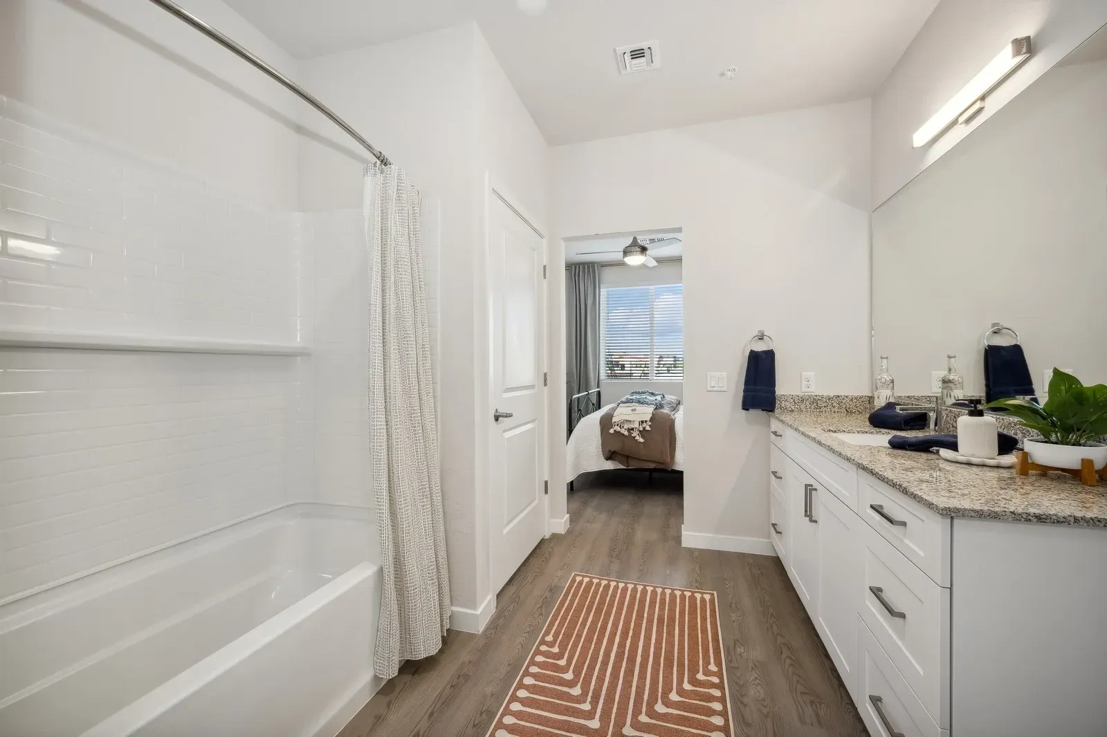 Bathroom with a bathtub, shower, vanity, and a glimpse of the bedroom at Longbow Luxury Apartments Mesa, AZ.