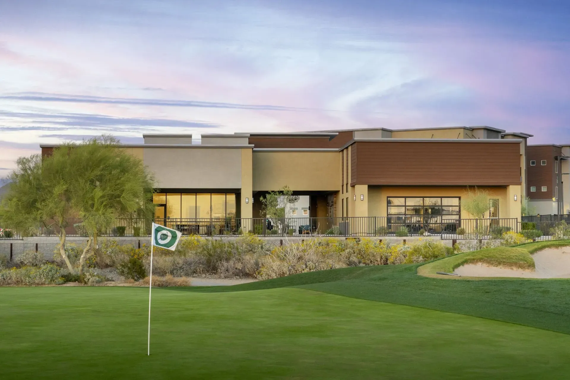 Golf course with a modern building and a flag on the green at Longbow Luxury Apartments in Mesa, AZ