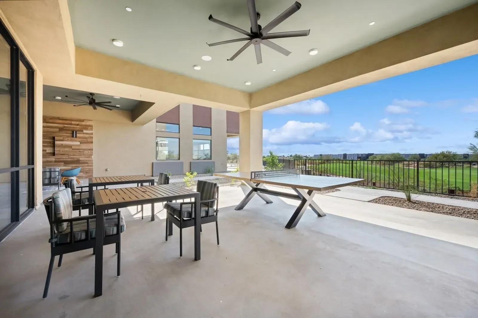 Outdoor patio with ping pong table and dining tables overlooking a golf course at Longbow Luxury apartments in Mesa, AZ.