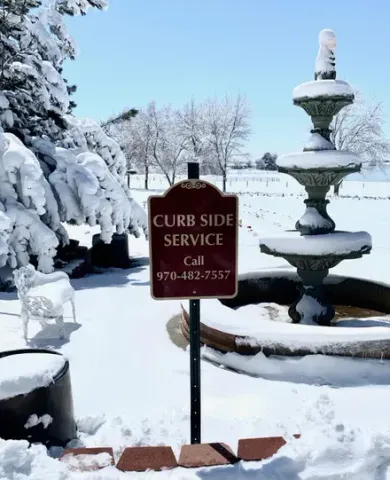 Snowy yard with a curbside service sign and a tiered fountain.