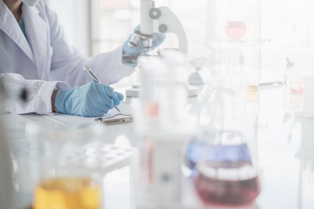 Scientist in Lab Coat, Gloves, and Mask Taking Notes — DAB Services in Cannonvale, QLD