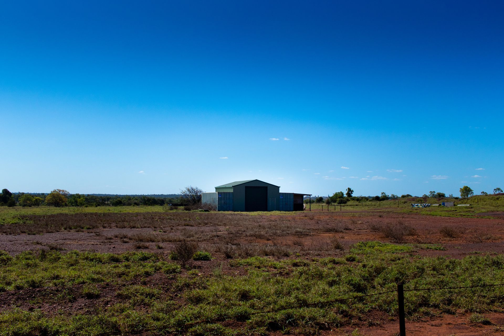 Metal Shed in a Field Under a Clear Blue Sky — DAB Services in Moranbah, QLD