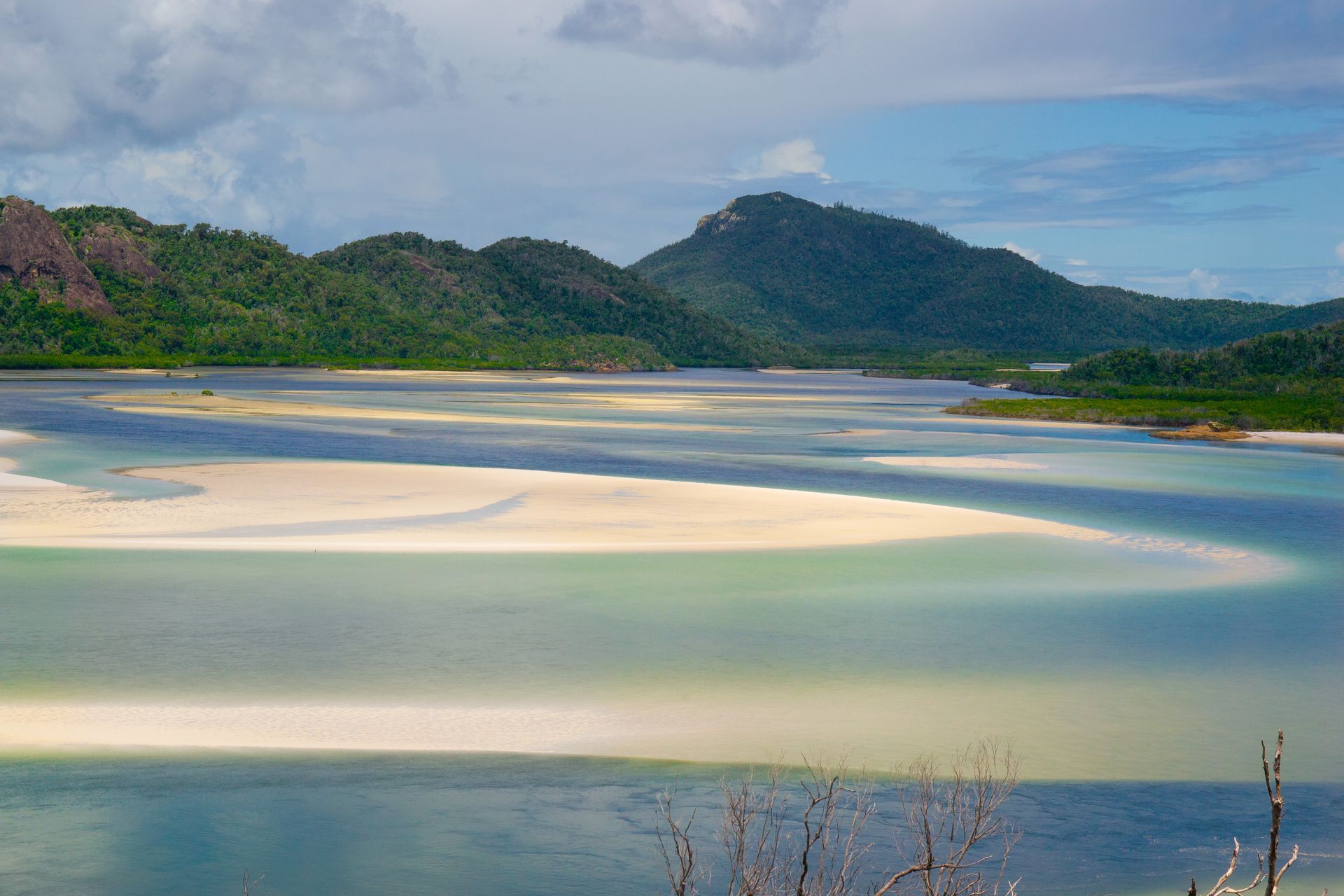 Lake with mountains in the background, blue sky, water, and green vegetation in the foreground — DAB Services in Cannonvale, QLD