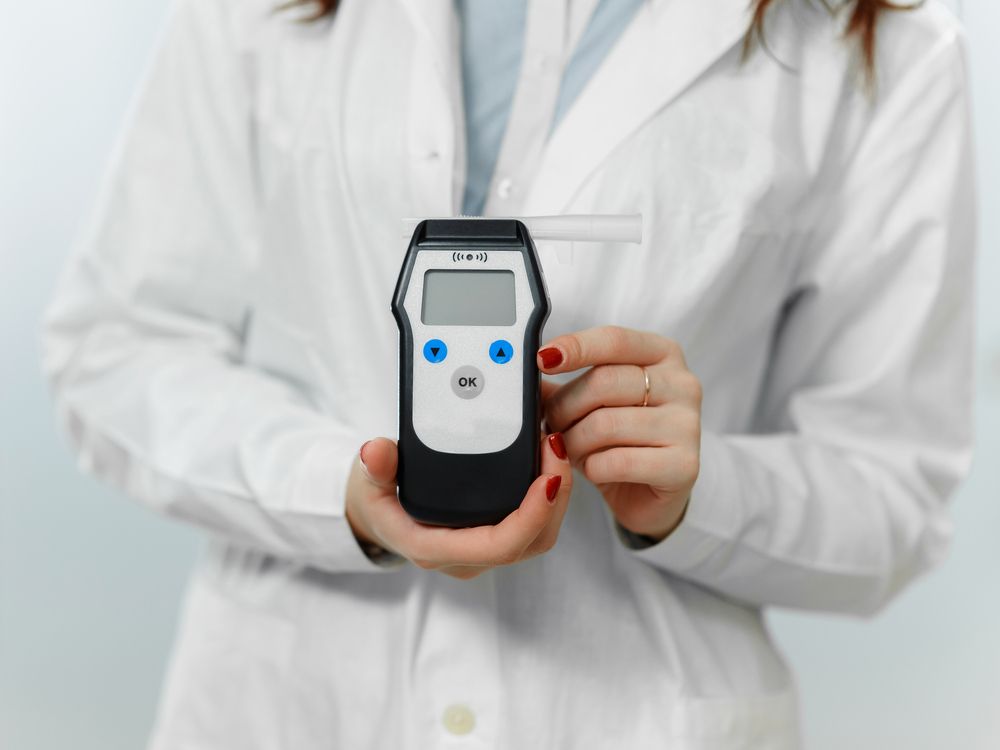 Person In Lab Coat Holding A Handheld Breathalyser — DAB Services in Bendigo, QLD