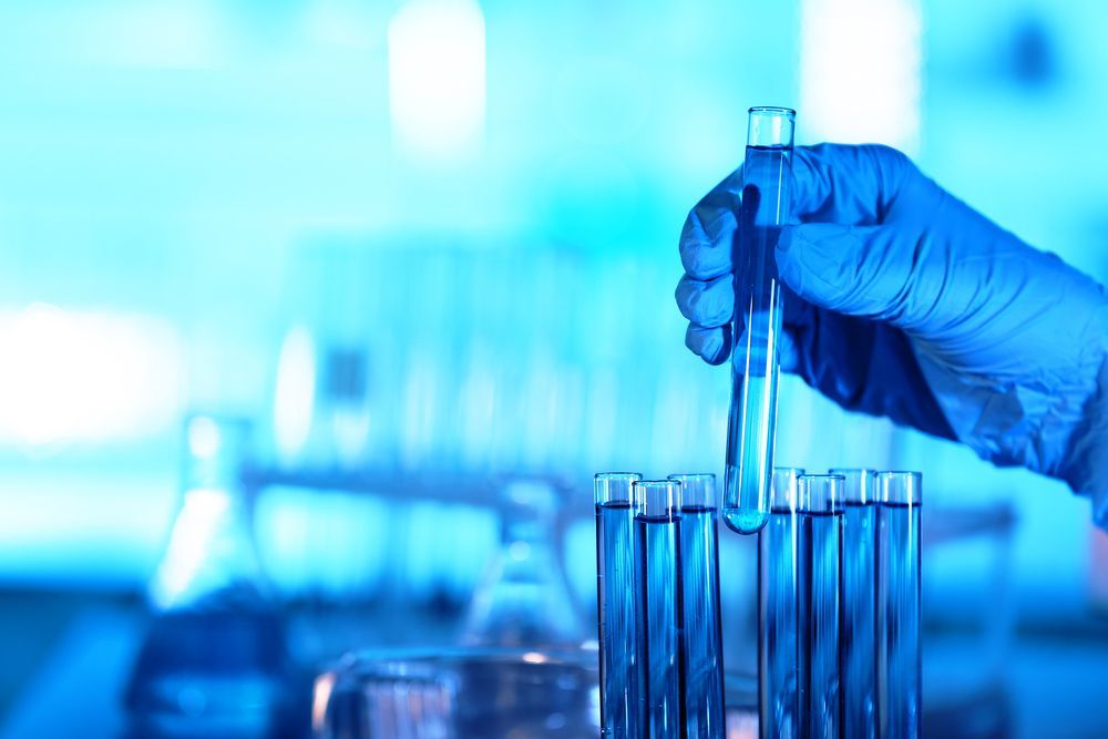 Person in Blue Gloves Holding a Test Tube With Blue Liquid in a Lab — DAB Services in Moranbah, QLD