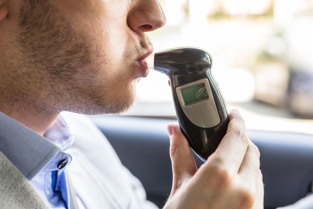 Man Blowing Into a Breathalyser in a Car; Testing Alcohol Level — DAB Services in Mackay, QLD