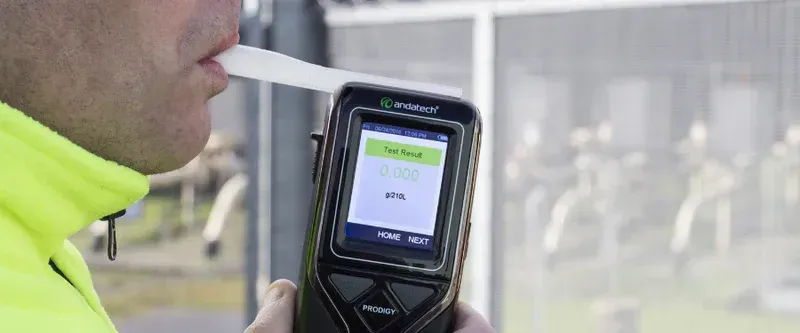Person Blowing Into A Breathalyser Held By A Person — DAB Services in Cannonvale, QLD