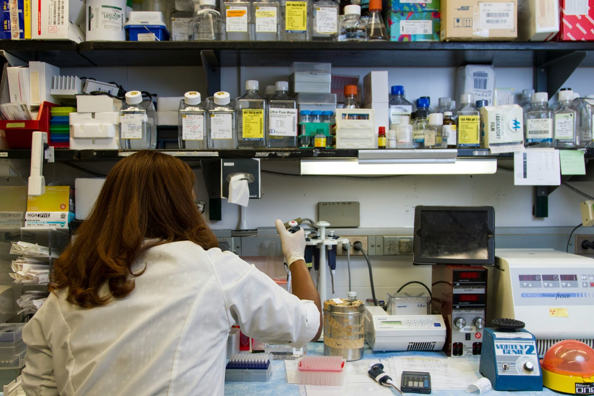 Scientist in lab coat using pipette at a lab bench with various scientific equipment — DAB Services in Cannonvale, QLD