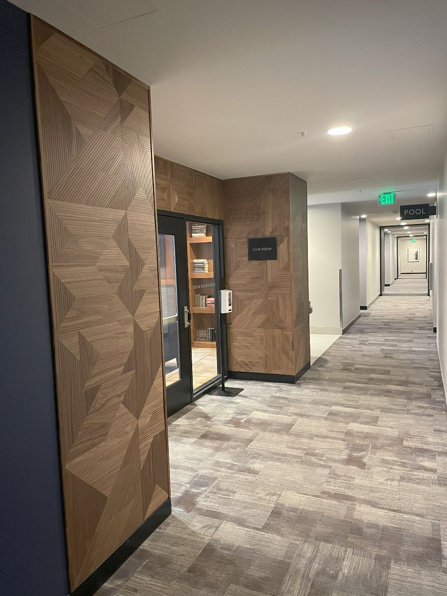 A long hallway with a wooden wall and a door leading to a room.