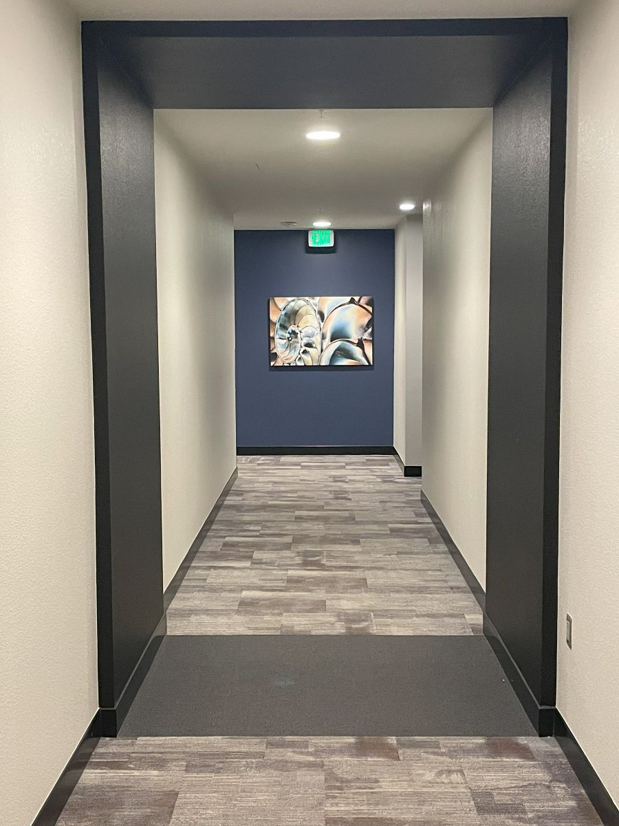 A hallway with a picture on the wall and an exit sign