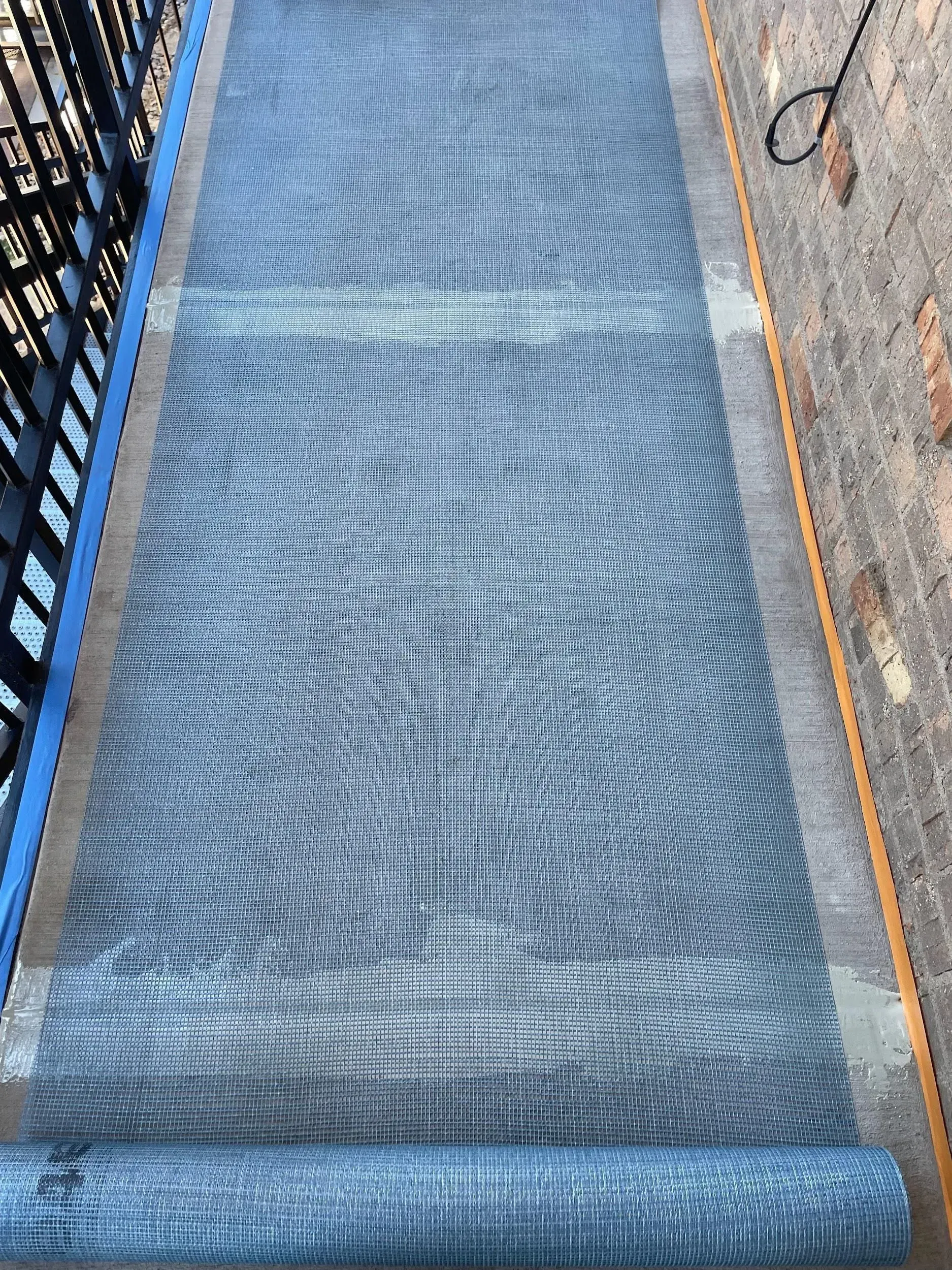 Blue patterned yoga mat rolled out on concrete surface.