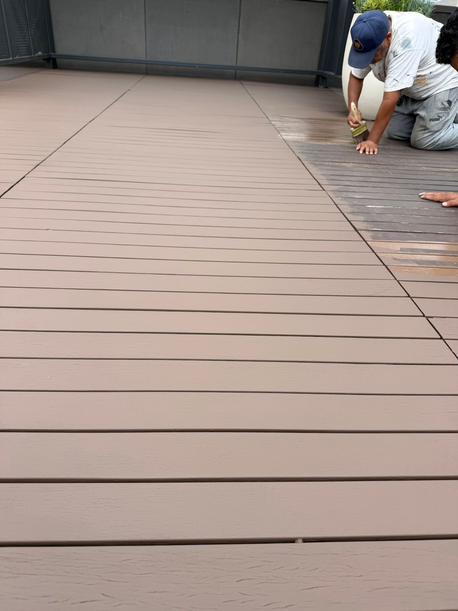 Worker installing light brown deck boards outdoors