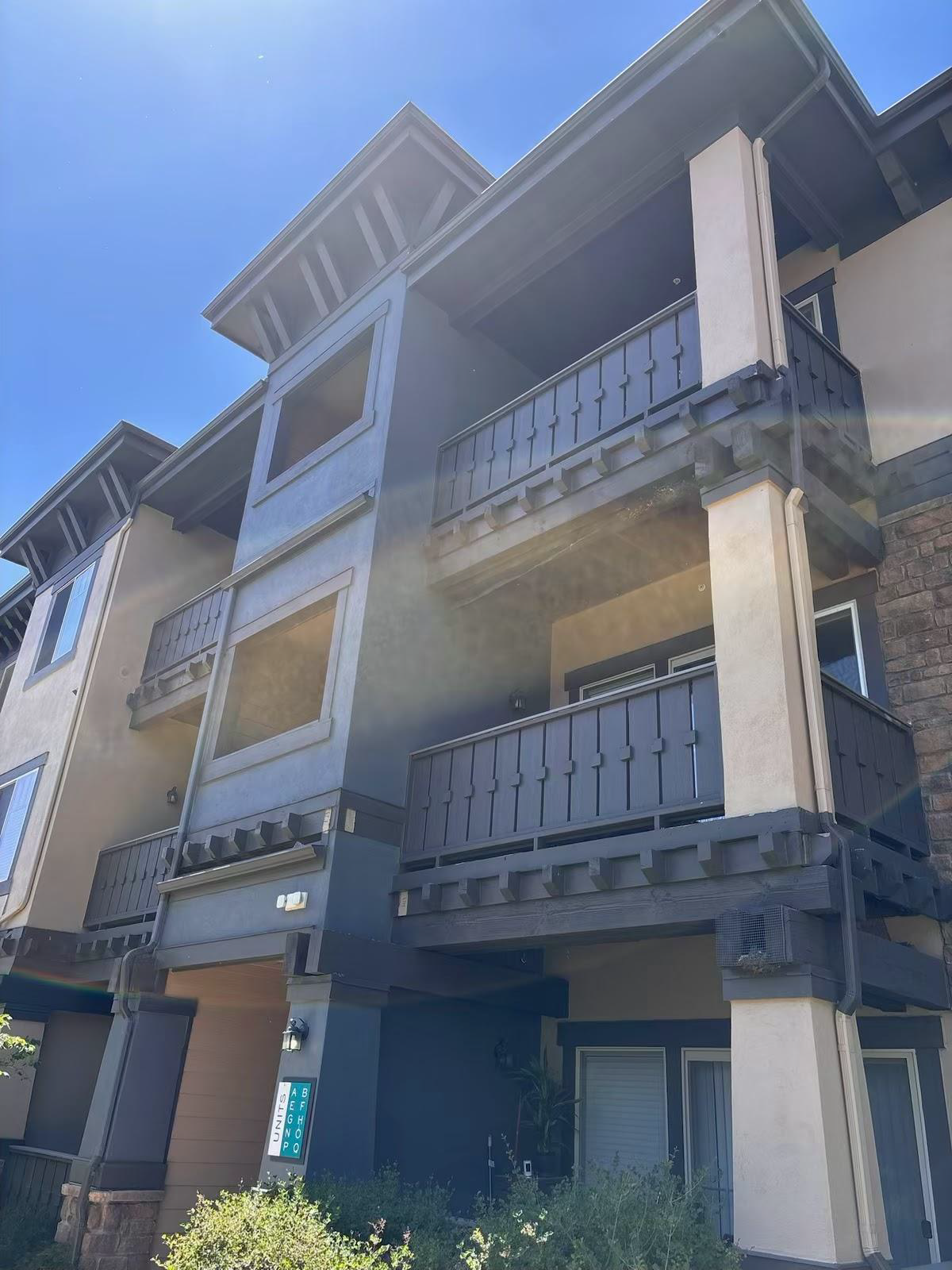 Multi-story apartment building with dark balconies and cream columns under a blue sky