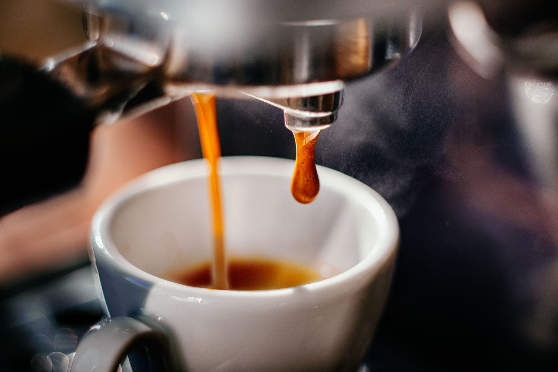 Espresso being made by Commercial Espresso Machine, liquid stream, white cup.