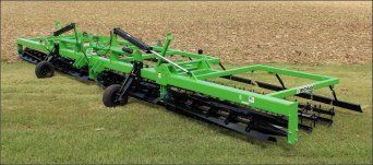 A green and black machine is sitting on top of a lush green field.