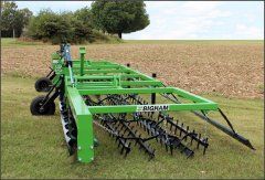 A green and black tractor is sitting on top of a lush green field.