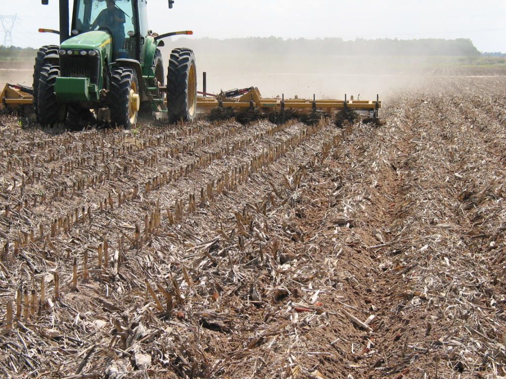 A tractor is plowing a field with a plow attached to it.