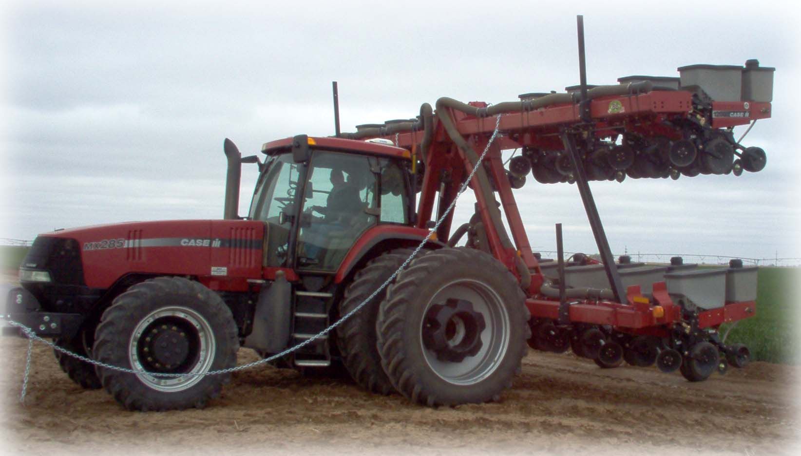 A red case tractor with a planter attached to it