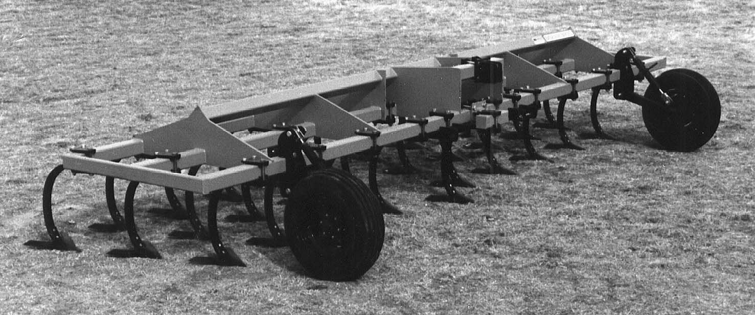 A black and white photo of a tractor with wheels on a dirt field.