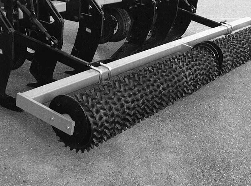 A black and white photo of a tractor with a roller attached to it.