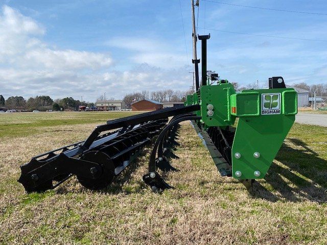 A green and black tractor is parked in a grassy field.