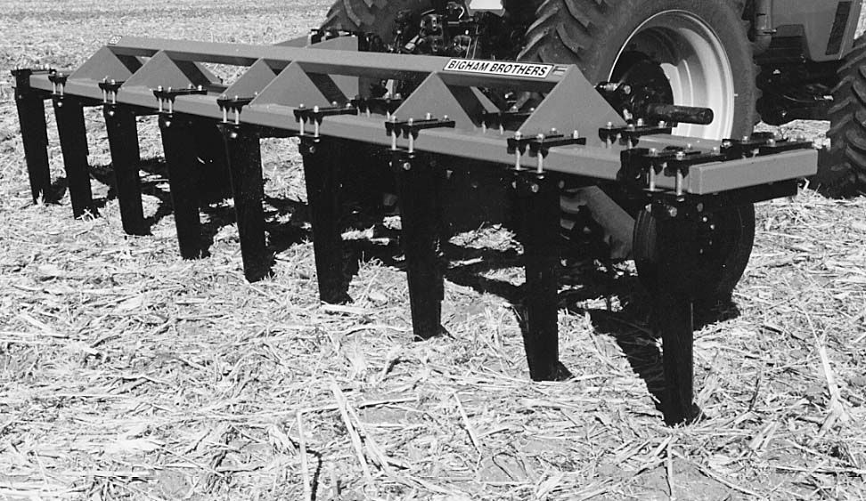 A black and white photo of a tractor with a plow attached to it