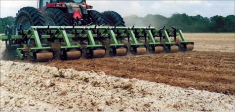 A tractor is plowing a field with a row of green planters