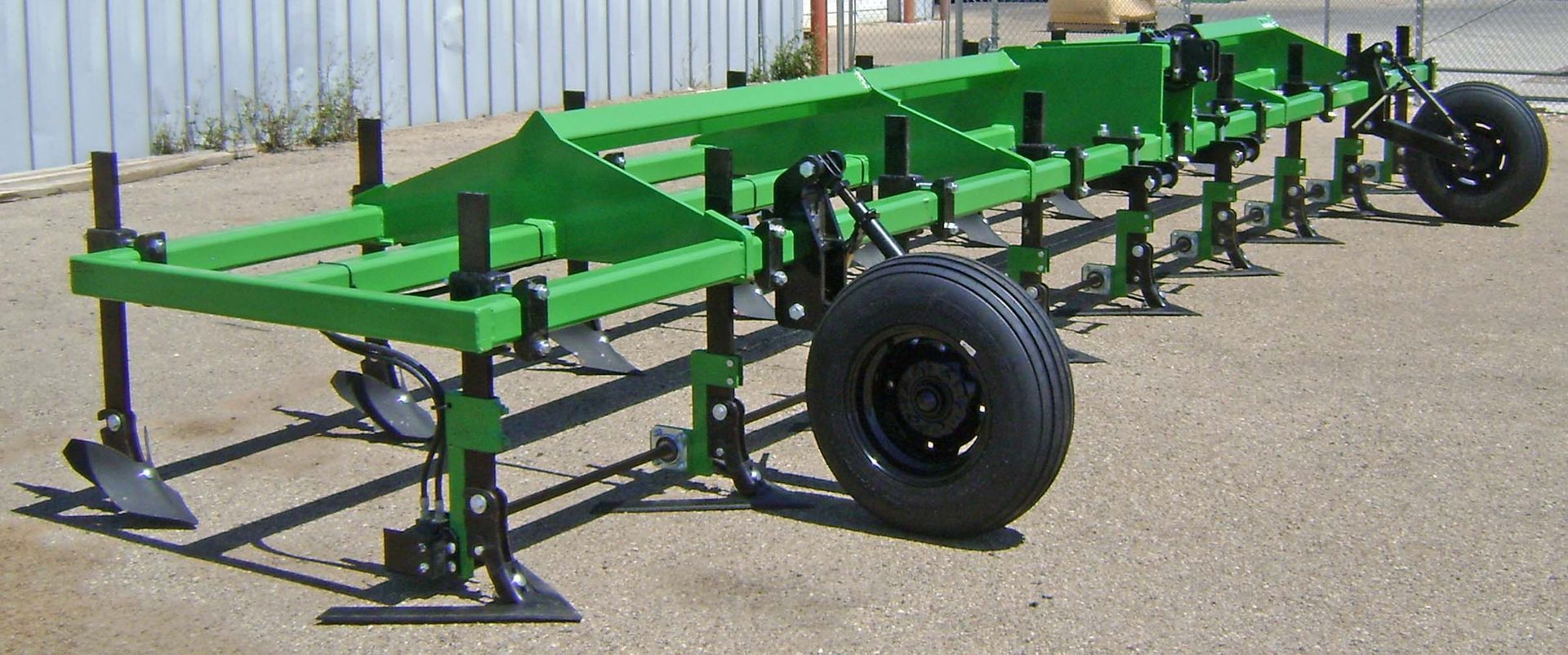 A green machine with black wheels is sitting on the ground