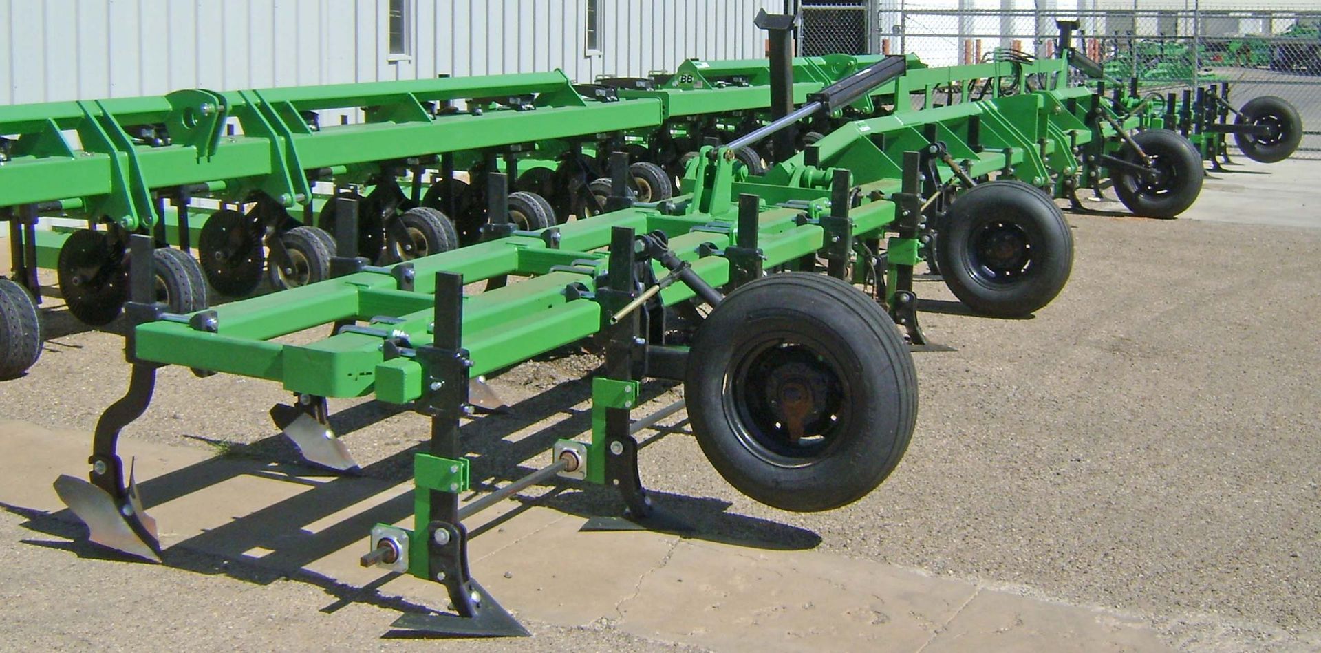 A row of green tractors are lined up in a parking lot