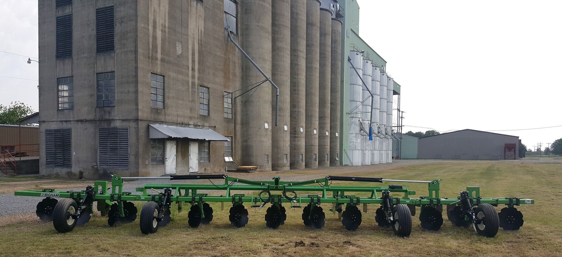 A row of green tractors are parked in front of a building