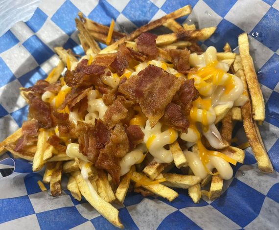 Loaded fries topped with melted cheese and bacon on blue checkered paper