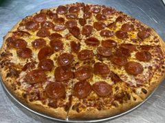 Pepperoni pizza on a metal tray, sliced into eight pieces