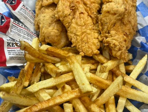 Fried chicken tenders, French fries, and ketchup packets on a takeout tray