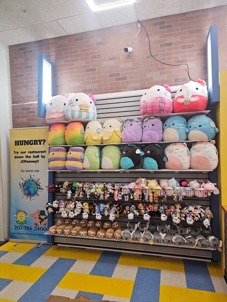 Prize booth with colorful plush toys stacked on shelves against a brick wall.