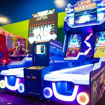 Colorful arcade racing game machines glowing blue and pink in a game center