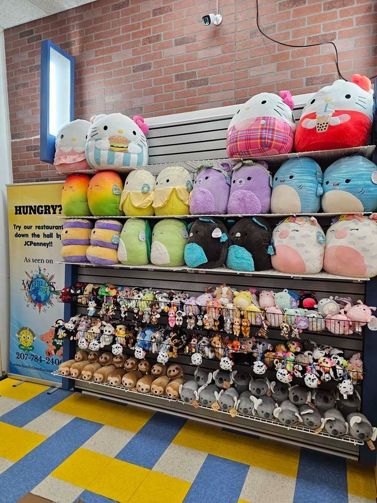 Plush toy display on shelves in a store, with colorful stuffed animals and keychains against a brick wall.