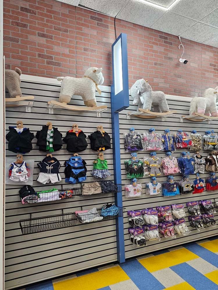 Pet store aisle with leashes, pet clothes, and plush dog beds on shelves against a brick wall.
