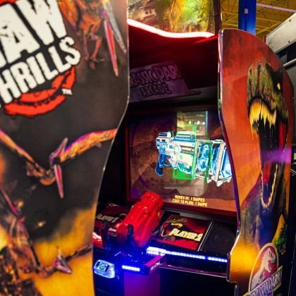 Arcade racing game cabinet with bright neon lights and colorful graphics showing a red toy car controller