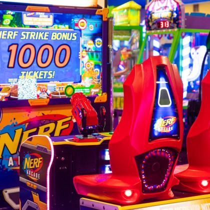 Nerf arcade game machine with red seats and a 1000 tickets bonus sign in a bright arcade