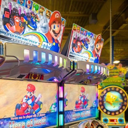 Mario-themed arcade machines with bright colorful screens and lights in an arcade